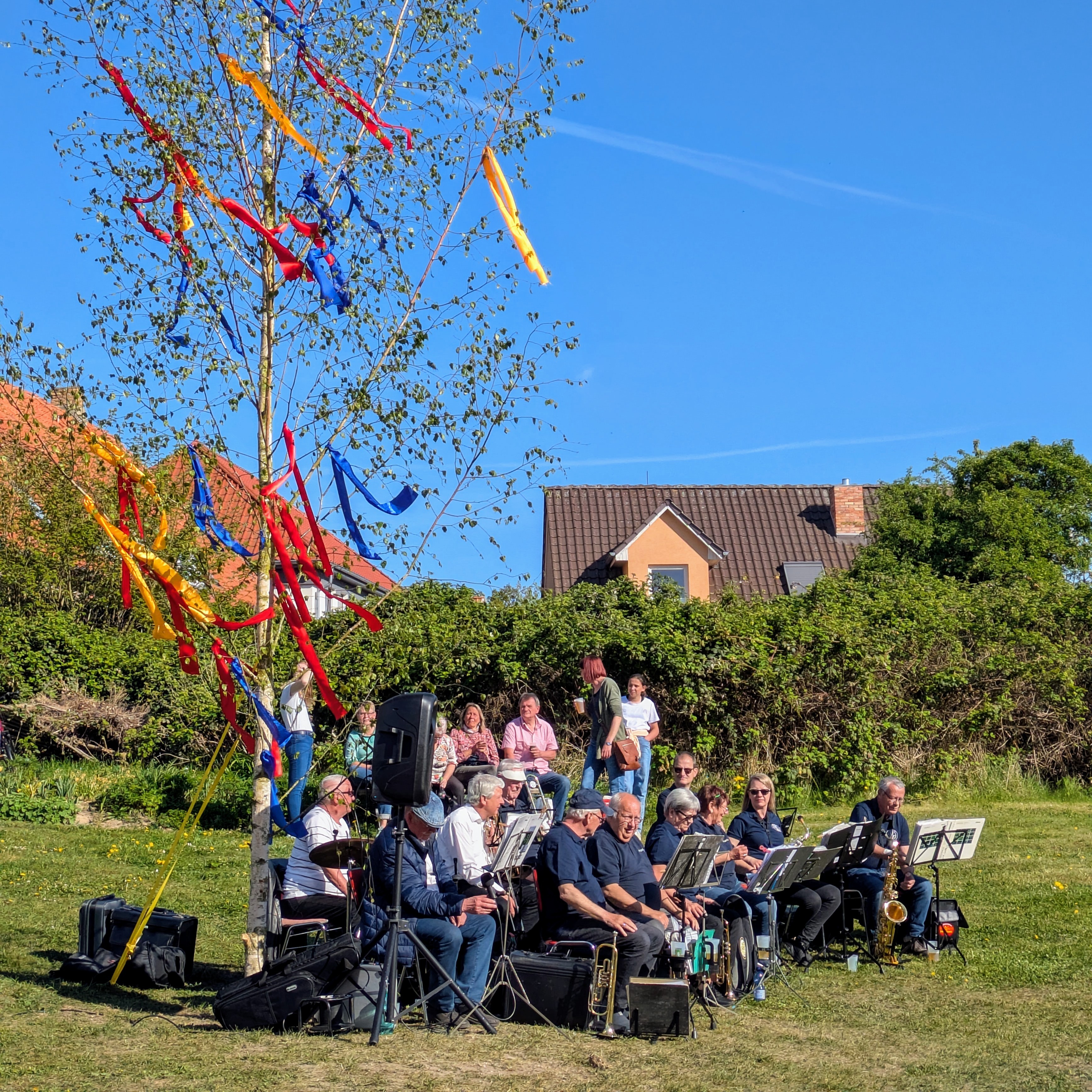 Maibaum mit bunten Bändern und Blasorchester der FFW im Vordergrund