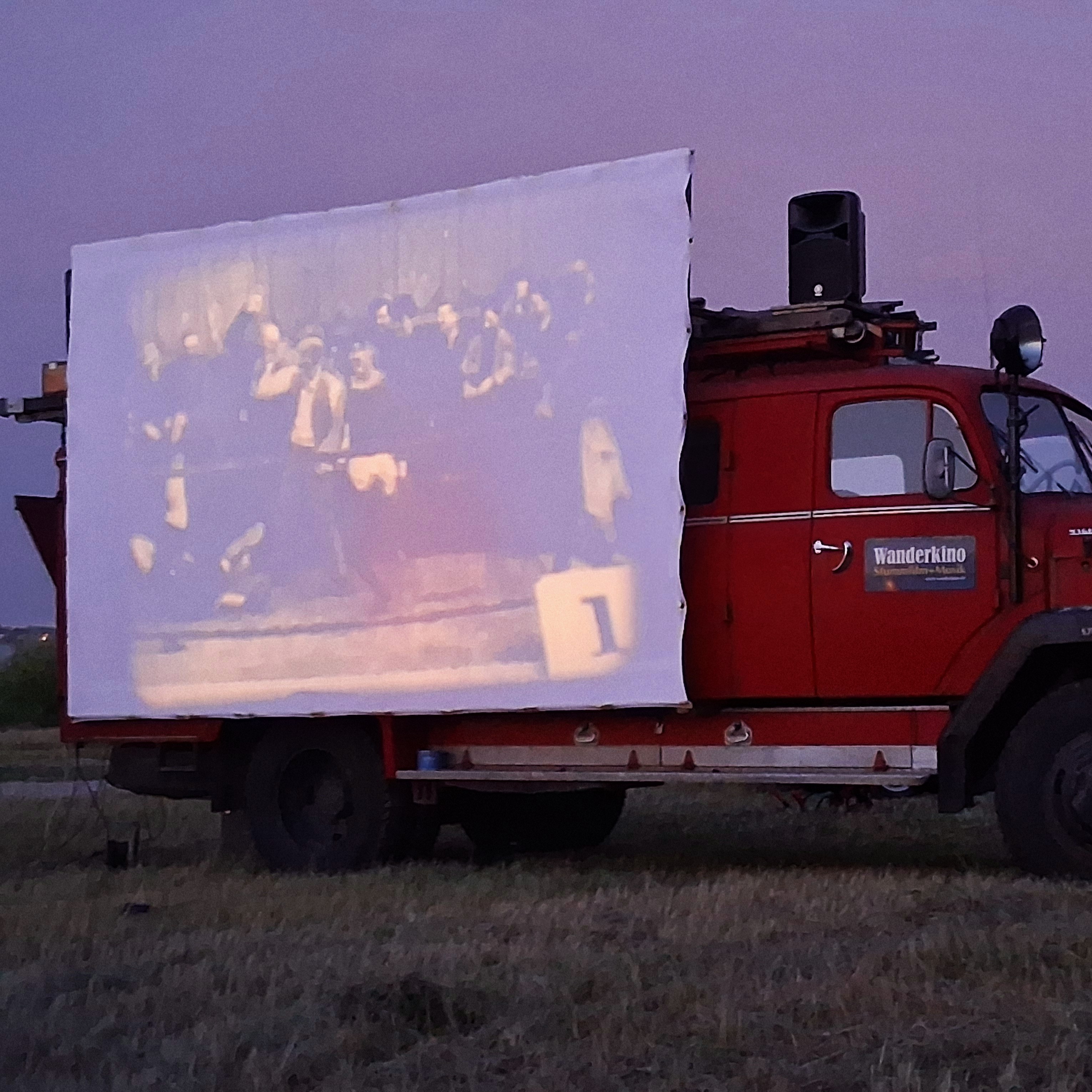 Ein rotes altes Feuerwehrauto umgebaut als Wanderkino 