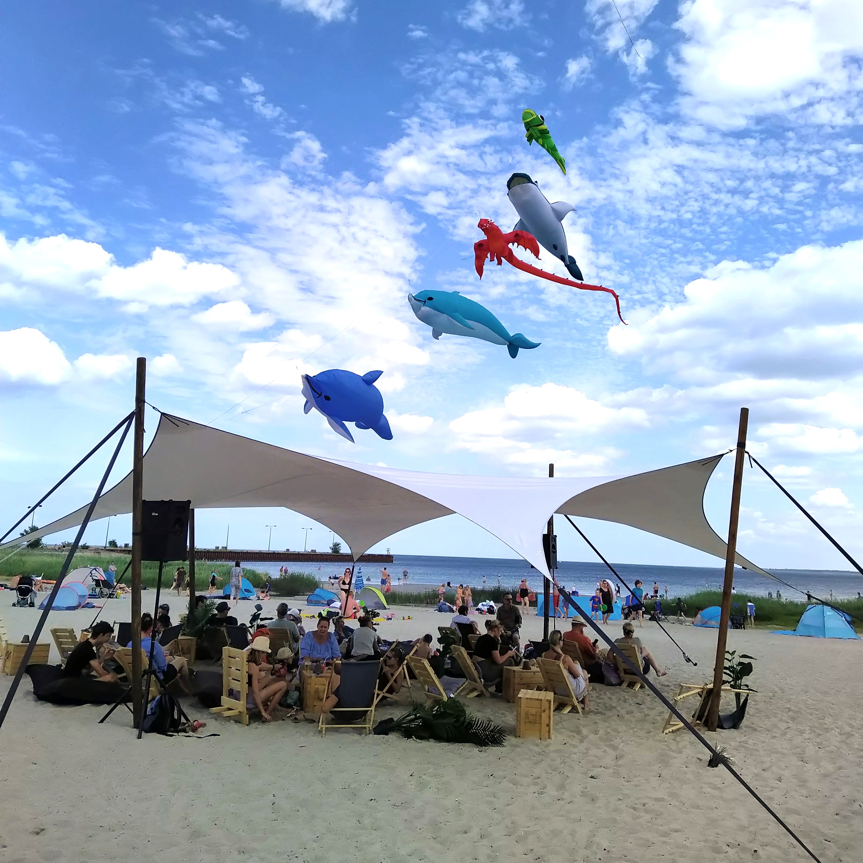Bunte Drachen am Himmel, Strandlounge mit Besuchern, im Hintergrund die Ostsee