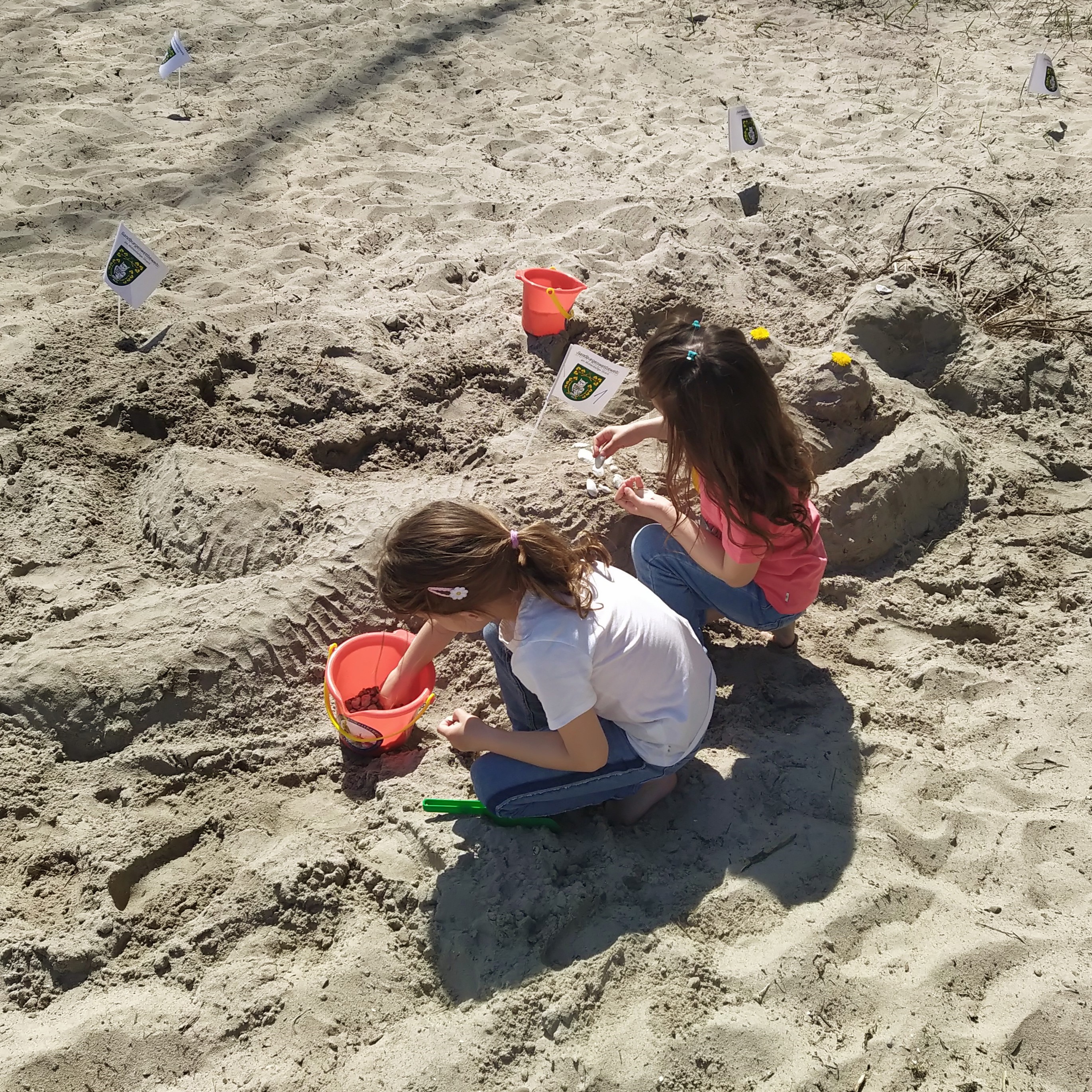 Kinder beim Sandburgenbauen am Strand.