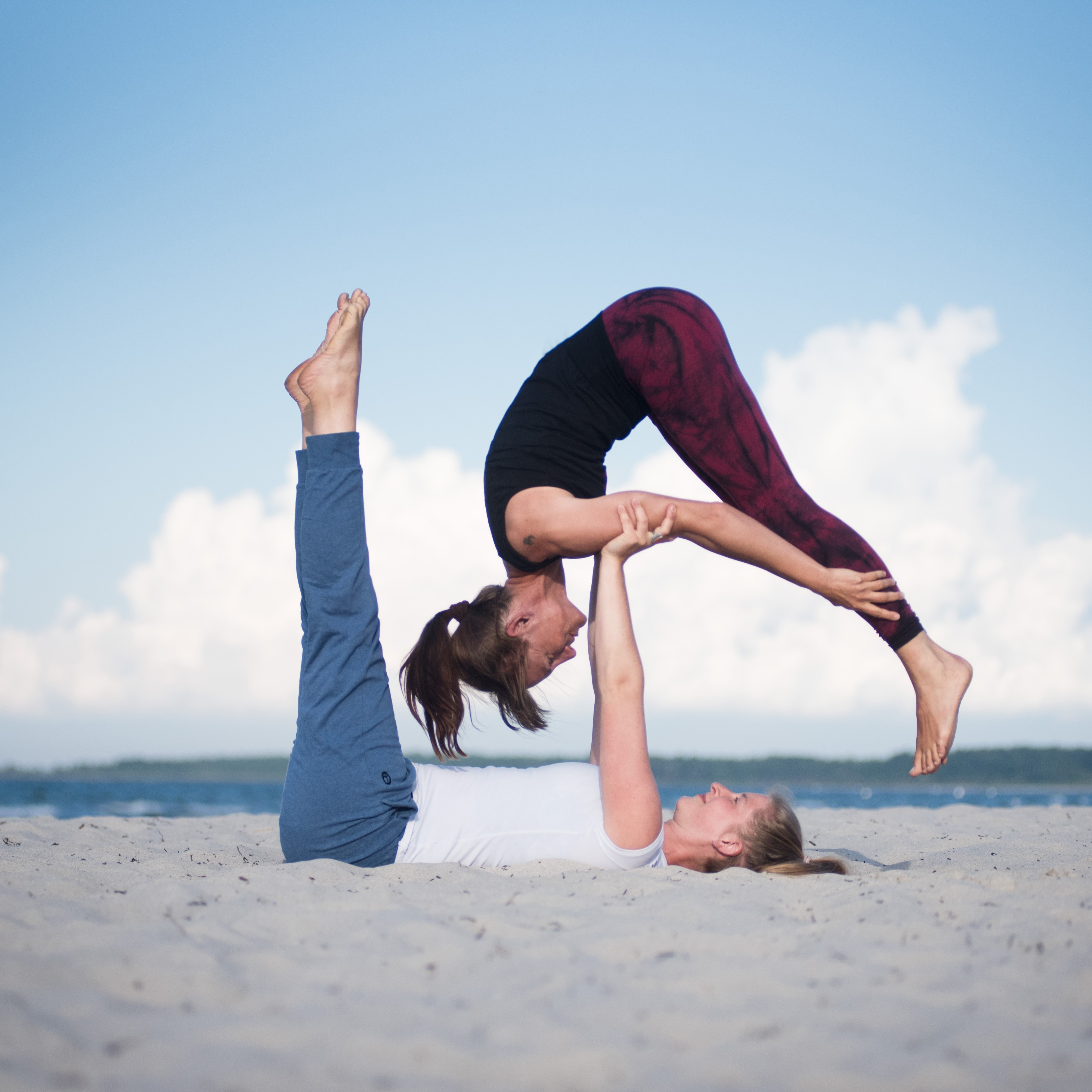 Zwei Personen beim Yoga am Strand.